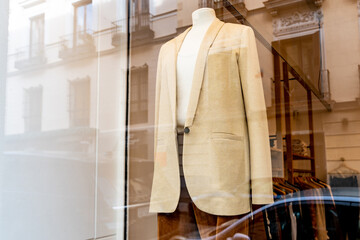Fototapeta na wymiar Mannequin in the window of a women's fashion store with a woman's jacket and blouse photographed from the street through the crystal