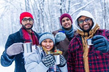 Happy young indian friends get warming with hot tea