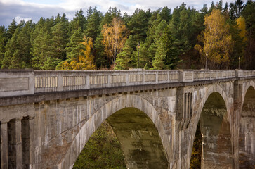 Stary betonowy most na wysokich filarach z lasem na horyzoncie na tle pięknego nieba.	
 - obrazy, fototapety, plakaty