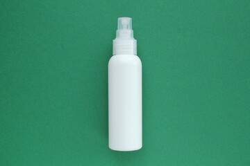 White unbranded plastic dispenser spray bottle on green background with copy space for text. Cosmetic package mockup, liquid soap flacon, hand sanitizer without label, shampoo organic spa, shower gel