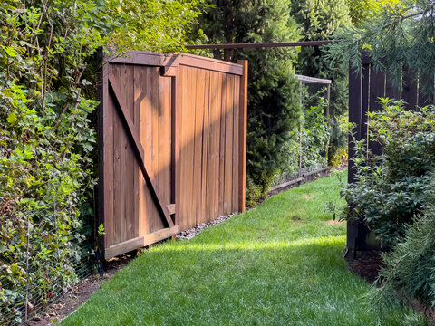 Beautiful View Of An Open Wooden Gate Leading Into A Lush, Green Backyard On A Sunny Day