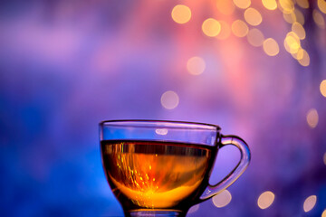 Christmas New Year background concept.
A cup of tea and a sparkling garland. Evening winter atmosphere
