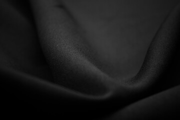 Texture of dark black fabric closeup. Low key photo. Plexus threads. Clothing industry. Abstract background. Black textile waves. Black cloth background