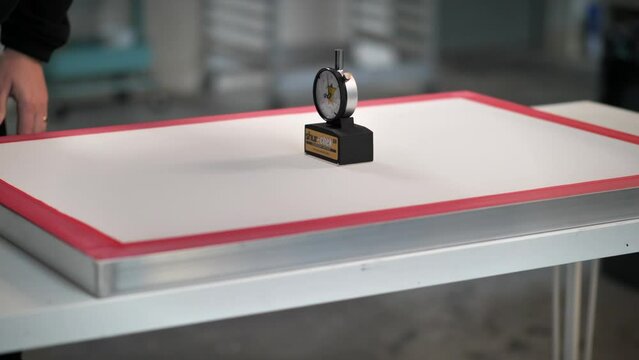 Measuring tension of screen printing screens with a newton meter to check quality of mesh.