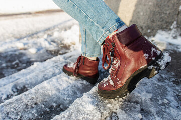 Winter is coming. Winter Female boots on rough slipper ice surface. A woman in vinous leather shoes...