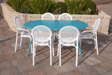 blue metal table with 6 white plastic chairs in the garden of the house, elegant luxury
