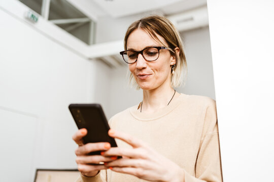 Young business woman with glasses looking at her cell phone