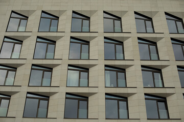 Fototapeta na wymiar Windows in building are textured. Modernist style in architecture. Repeating element.
