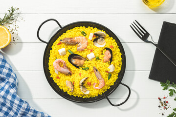 Seafood paella on traditional paella pan on white wooden base .Top view.