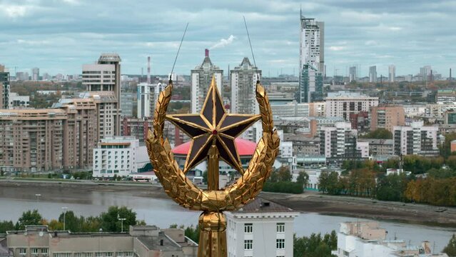 Aerial view of a building top, historical element of a roof. Stock footage. Golden spire with USSR star on the background of a city.