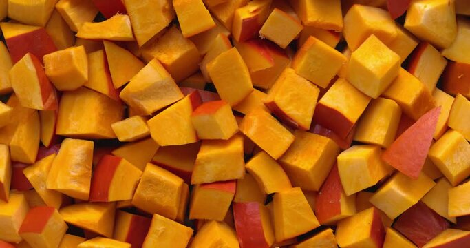 Chopped red kuri squash chunks background texture. Table spin.