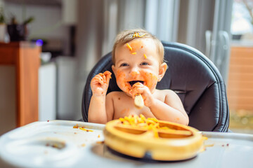 Little baby girl eating her dinner and making a mess