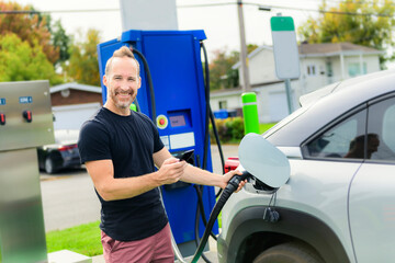 man inserts plug into the electric car charging socket