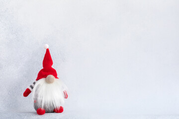 Christmas gnome in red hat holiday banner on light winter background. Scandinavian troll greeting card with copy space