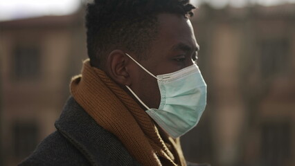 African male walking outside during winter wearing covid surgical face mask outside2
