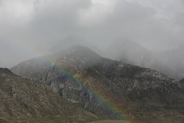 Low clouds partly hide the mountain tops in Northern Utah while the low angle sunlight creates a brief rainbow.