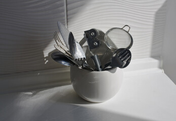 Kitchen utensils in a white container on a white background	
