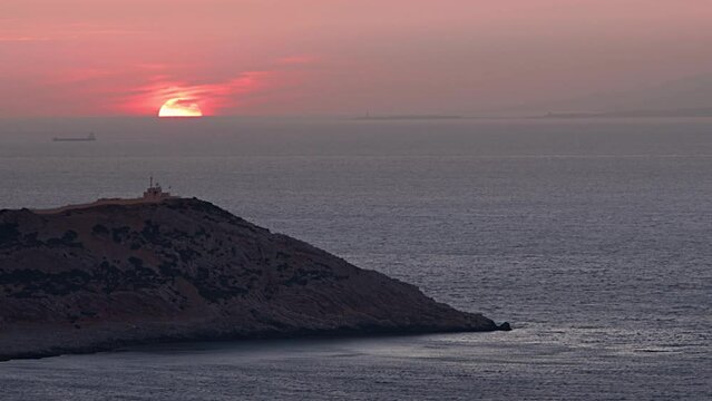 Sunset over the horizon at sea while crossing a ship and land sleeve against the light
