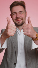 Like. Bearded adult business man raises thumbs up agrees with something or gives positive reply recommends advertisement likes good. Young guy isolated alone on pink studio background. Vertical view