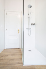 White bathroom with shower and golden lamp. Wood imitation floor