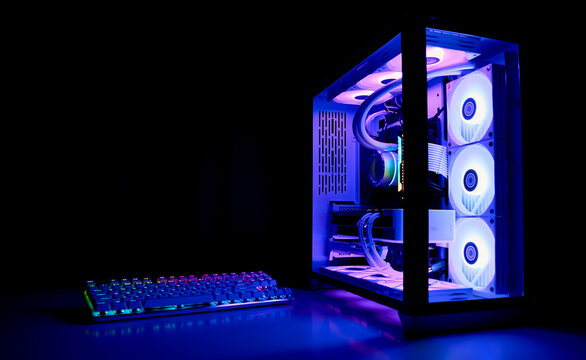 Water Cooled Gaming Pc with RGB rainbow LED lighting. Modern gaming computer with a keyboard in a dark room. Water Liquid Cooling Computer.