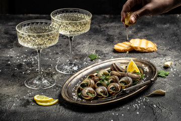 Fried snails Escargots de Bourgogne with herbs, butter, garlic on metal plate with forks, wine glass. gourmet food. Restaurant menu, dieting, cookbook recipe
