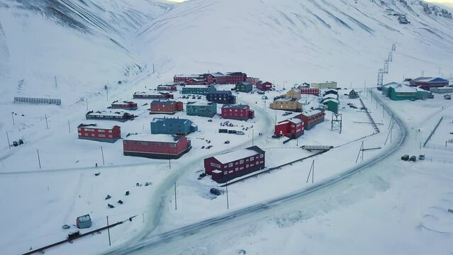 Aerial view of Longyearbyen, Svalbard in winter. With colorful houses, snow-capped mountains, with avalanche protection and fjord. Drone flight. High quality 4k footage