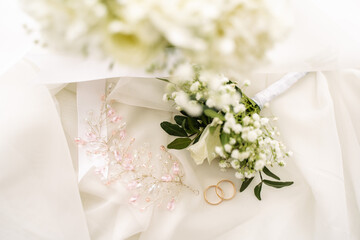 wedding rings along with jewelry and a boutonniere on the veil