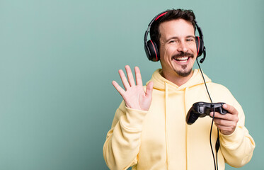 adult man smiling happily, waving hand, welcoming and greeting you with headset and a control. gamer concept © kues1