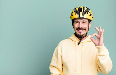 adult man feeling happy, showing approval with okay gesture. bike helmet and bicycle concept