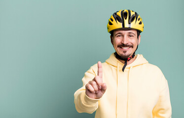 adult man smiling proudly and confidently making number one. bike helmet and bicycle concept