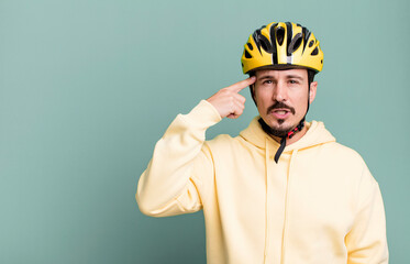 adult man feeling confused and puzzled, showing you are insane. bike helmet and bicycle concept