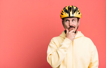 adult man thinking, feeling doubtful and confused. bike helmet and bicycle concept