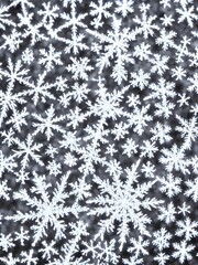 Fototapeta premium The photo is of a delicate snowflake, suspended in midair. It's well-defined edges are shining brightly against the dark background. The center of the flake looks like it has been cut out, revealing i