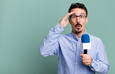 adult man looking happy, astonished and surprised with a microphone. presenter or journalist concept