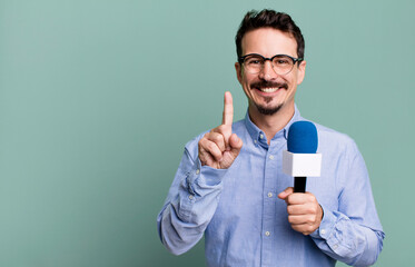 adult man smiling proudly and confidently making number one with a microphone. presenter or...