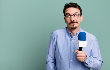 adult man shrugging, feeling confused and uncertain with a microphone. presenter or journalist...