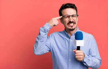 adult man feeling confused and puzzled, showing you are insane with a microphone. presenter or...