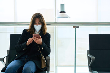 pretty brunette girl with protective mask looks at the mobile
