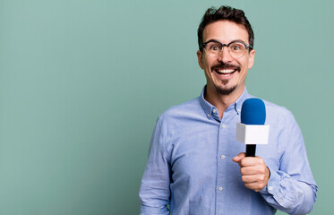 adult man looking happy and pleasantly surprised with a microphone. presenter or journalist concept