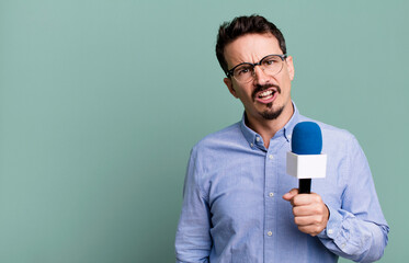 adult man feeling puzzled and confused with a microphone. presenter or journalist concept