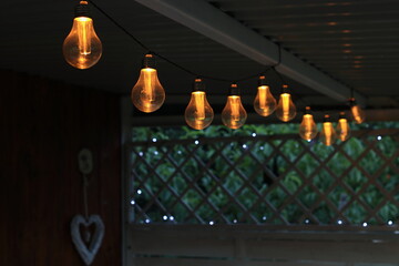 Solar lamps lit in the evening in the garden gazebo. - obrazy, fototapety, plakaty