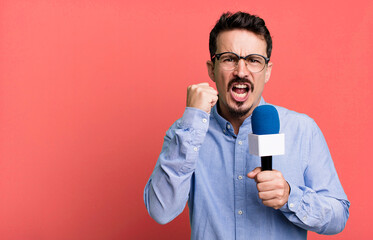 adult man shouting aggressively with an angry expression with a microphone. presenter or journalist...