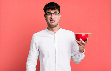 adult man feeling puzzled and confused holding a ramen noodles bowl