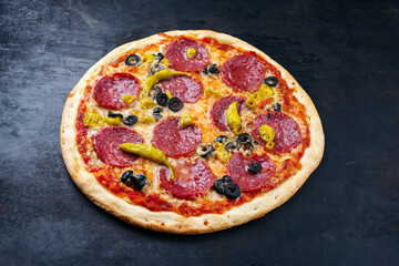 Traditionelle italienische Pizza al salame mit Salami, Mozzarella und Oliven serviert als close-up auf einem alten rustikalen Board mit Textfreiraum 