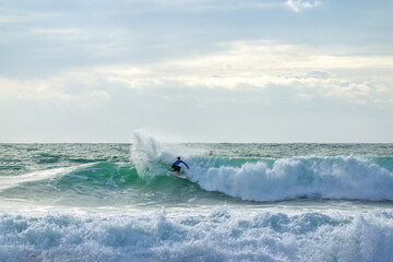 Fototapeta premium Gorgeous view on urfer ride the wave, many splashes in sunbeams on surfing competetion Moche Rip Curl Pro Portugal 2015