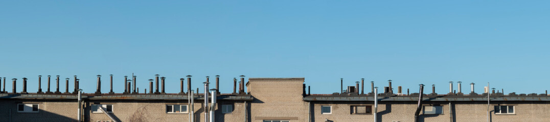 A row of air duct and chimneys on the top of the roof, panoramic view