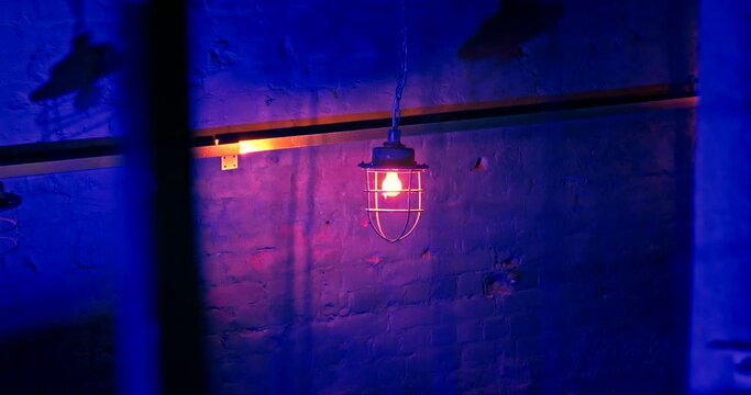 Swinging loft-style lanterns suspended from long chains in a nightclub against a brick wall. Concert concept. Shadows on the brick wall of the club. Blue Neon lighting in the pub.