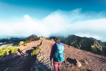 Woman hiking along scenic hike trail to Pico Ruivo in the morning. Pico do Arieiro, Madeira Island,...