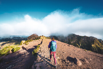 Naklejka premium Woman hiking along scenic hike trail to Pico Ruivo in the morning. Pico do Arieiro, Madeira Island, Portugal, Europe.